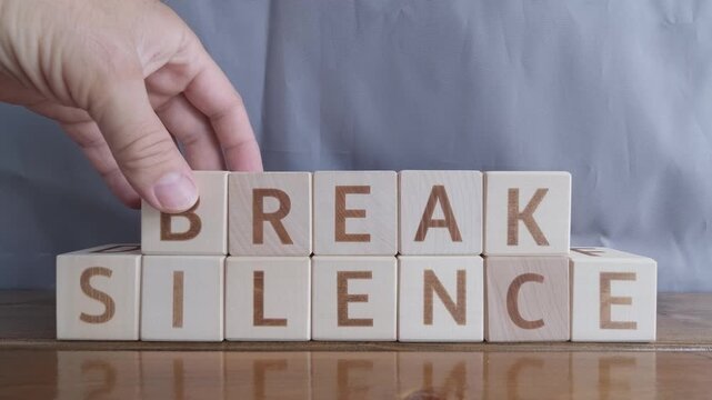 motivational word Break silence, laying out by hand from letters on wooden cubes, slow motion

