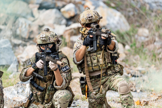 Military personnel practice tactical movement during training exercise in a rocky terrain