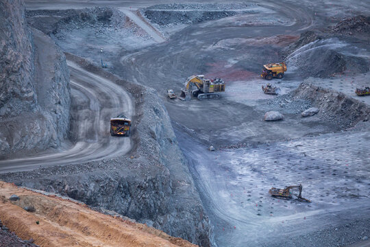 View of the Super Pit open-pit gold mine with heavy mining machinery including dump trucks and excavators operating on rocky terraces in Kalgoorlie - Boulder, Western Australia, Australia.