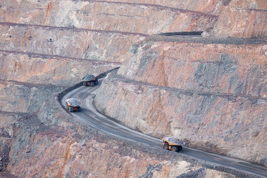 View of the Super Pit open-cut gold mine with large haul trucks driving along the winding dirt roads of the terraced rock walls in Kalgoorlie-Boulder, Western Australia, Australia.