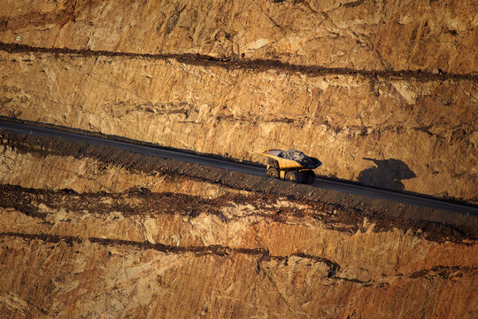 View of a large mining haul truck driving along a terraced road in the Super Pit open-cut gold mine in Kalgoorlie - Boulder, Western Australia, Australia.