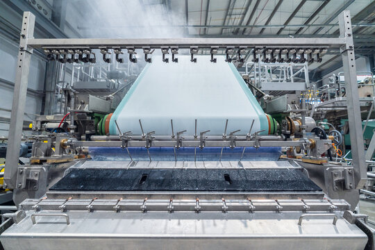 View of an industrial paper manufacturing machine with rollers and conveyor belts in a factory setting in Berlin, Berlin, Germany.
