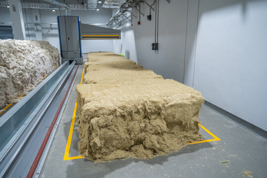 View of automated fiber testing machinery processing large bales of raw hemp fiber in an industrial facility in Berlin, Berlin, Germany.
