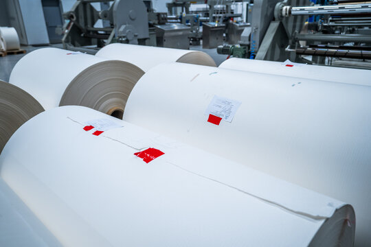 View of large rolls of white paper in an industrial factory setting with machinery in the background in Berlin, Berlin, Germany.