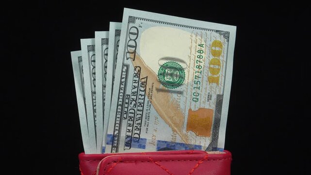 Five crisp 100 dollar bills inside a red leather wallet representing American currency personal savings financial security and everyday money management