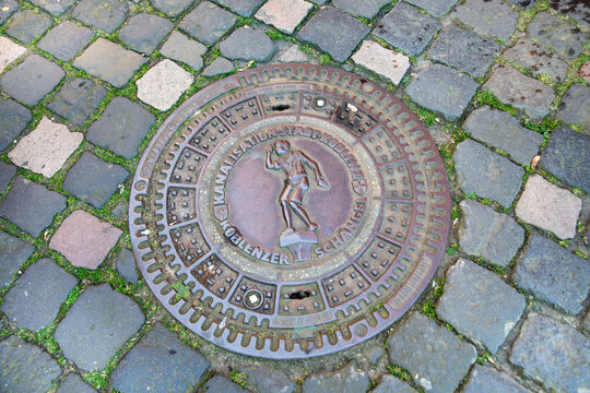 decorative manhole cover from Koblenz, Germany, featuring a relief of the Koblenzer Sch&auml;ngel, a famous local symbol and dialect term for a boy born in the city