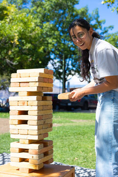 Smiling woman holding a block beside a wooden game tower