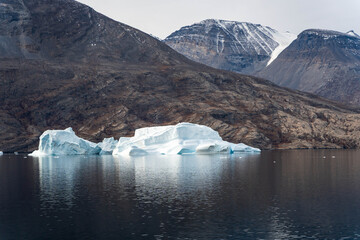 Iceberg in East Greenland floating at sunset in still water © Michael