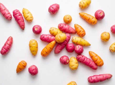 Brightly coloured oca tubers scattered on a white surface seen from above