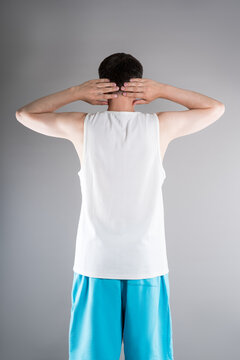 Unrecognizable man in sportswear performs exercises for muscles of upper back, arms and shoulder joint. Posture correction and physical therapy