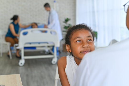 A young girl smiles while speaking to a doctor in a bright hospital room, symbolizing hope and care in healthcare settings for children.