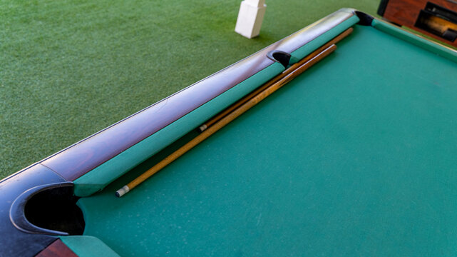 Billiard Cues Resting on Green Pool Table