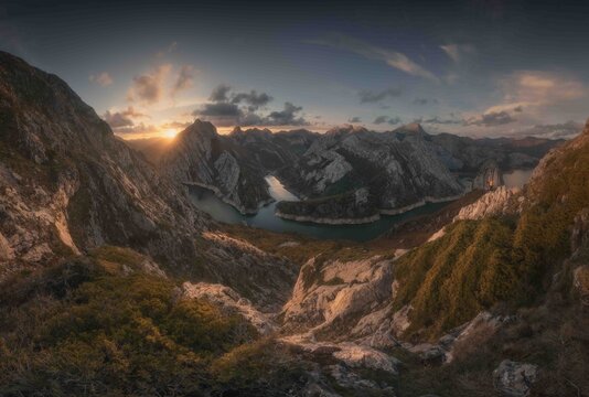 View of a winding river flowing through rocky mountain peaks at sunset in Spain.