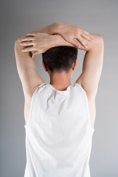 Unrecognizable man in sportswear performs exercises for muscles of upper back, arms and shoulder joint. Posture correction and physical therapy