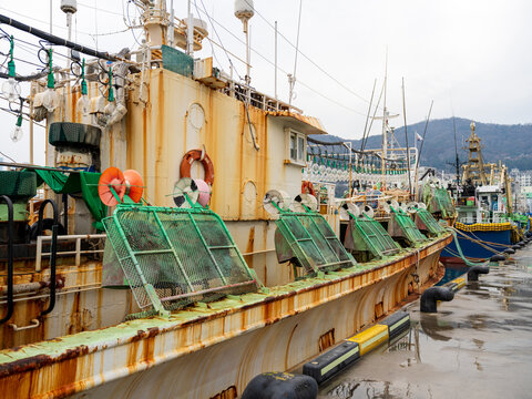 View of a weathered fishing boat with a rusted hull and fishing nets docked at the harbor in Busan, Busan, South Korea.