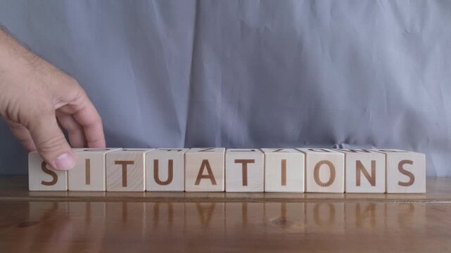 motivational word Situations, laying out by hand from letters on wooden cubes, slow motion
