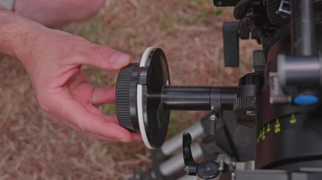 Close-Up of Focus Puller Turning Follow Focus Wheel to Shift Lens Distance Scale on Cinema Camera