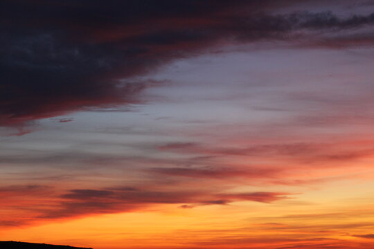 View of a vibrant sunset sky with dramatic orange, red, and purple clouds over the Peak District National Park in England, United Kingdom.