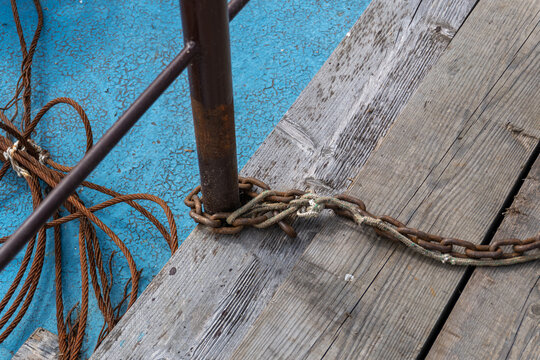 Metal chain wrapped around iron post on wooden dock