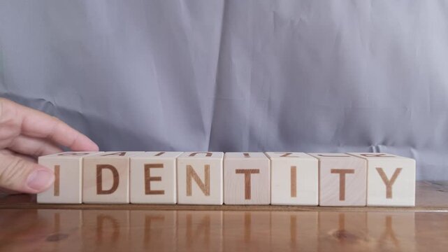 motivational word Identity, laying out by hand from letters on wooden cubes, slow motion
