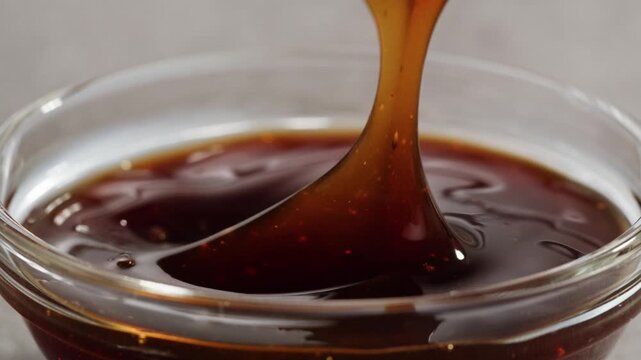 Dip with soy sauce Japanese brown teriyaki sauce in the spoon with circle rotation close up, sweet chilli in fast food restaurant