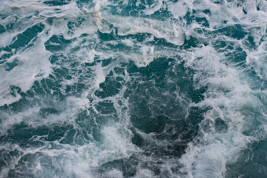 View of turbulent ocean waves with white sea foam swirling in the deep blue water of the Atlantic Ocean in Madeira, Portugal.
