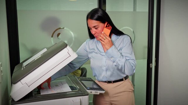 Professional Woman Using A Copy Machine While Talking On The Phone In An Office