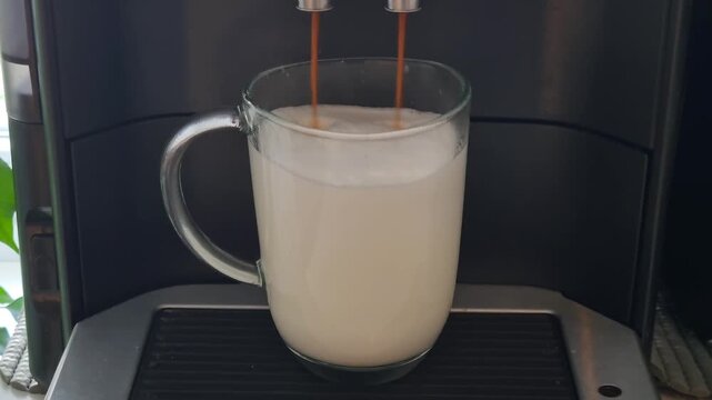 Mainz, Rhineland Palatinate, Germany: Coffee machine preparing creamy latte macchiato with milk foam in glass cup.