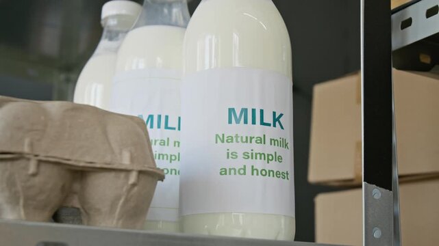 Bottled organic milk standing beside carton eggs on metal storage shelf in grocery warehouse. Footage suitable for organic dairy farming commercials and retail food store marketing