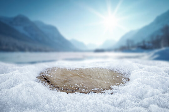 Empty wooden board with copy space in snowy winter landscape &ndash; seasonal product concept.
