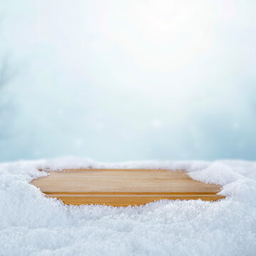 Empty wooden board with copy space in snowy winter landscape &ndash; seasonal product concept.