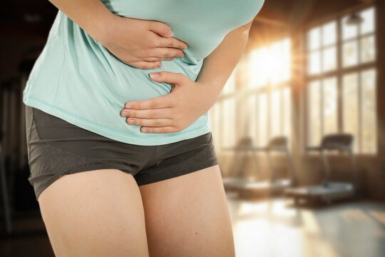 Woman stretching and massaging painful body areas of stomach&ndash; muscle pain and health concept.
