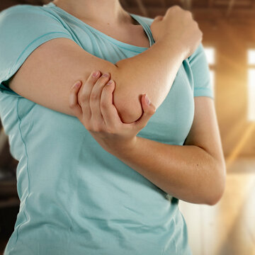 Woman stretching and massaging painful body areas of arm and elbow&ndash; muscle pain and health concept.