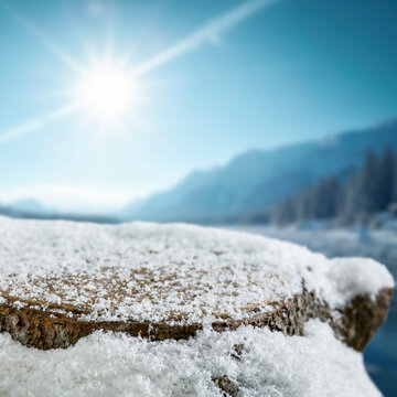 Empty covered with snow tree trunk for product placement, surrounded by fresh snow and a beautiful winter landscape in the background.