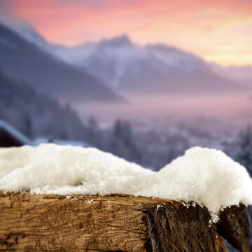 Empty covered with snow tree trunk for product placement, surrounded by fresh snow and a beautiful winter landscape in the background.