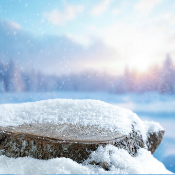 Empty covered with snow tree trunk for product placement, surrounded by fresh snow and a beautiful winter landscape in the background.
