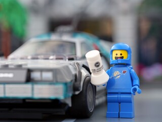 Fototapeta premium Tambov, Russian Federation - September 17, 2026 Blue Lego spaceman minifigure holding a Mr. Fusion generator next to the DeLorean time machine.