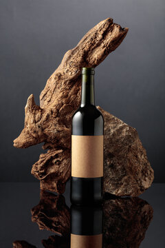 Bottle of red wine with old driftwood and a piece of granite rock.