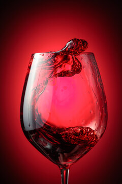 Wine glass with red liquid frozen in movement.