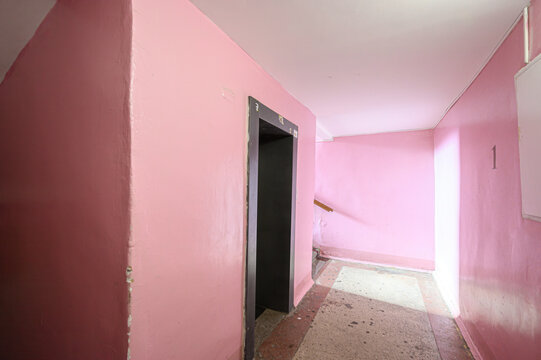 Soviet-era hallway: muted pink walls, worn floor tiles, open doorway, number 1 on wall, plain ceiling, utilitarian design