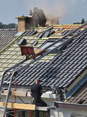 Ouvriers qui rénovent la toiture d’une maison pour isolation et remplacement des tuiles © joef