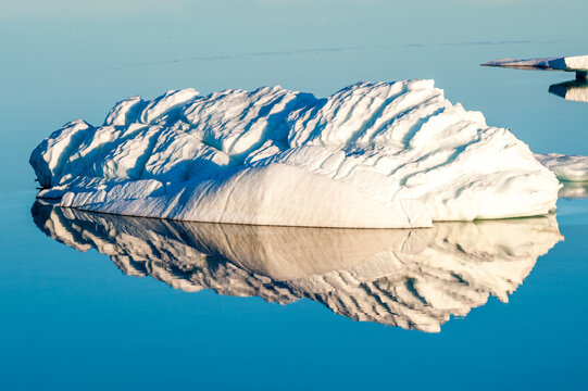 Striated iceberg with reflection in calm water