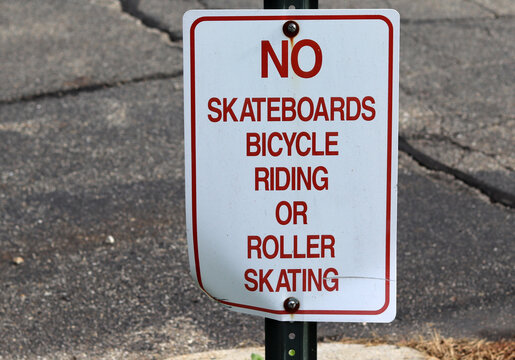 Red and white regulatory sign reading No Skateboards Bicycle Riding or Roller Skating