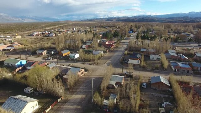 4K drone aerial view over Lago Posadas village in Santa Cruz, Argentina, revealing homes surrounded by rugged Patagonian landscapes, arid terrain and remote wilderness scenery.