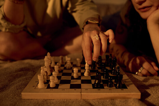 Close up of Caucasian young adult couple playing chess at home, making strategic move. Image suitable for relationship advice, leisure lifestyle, board games marketing