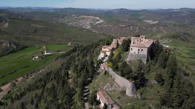 Stunning aerial drone panorama of medieval Montebello Castle perched on a rocky hill surrounded by lush green valley and historic village in Poggio Torriana, Emilia-Romagna, Italy
