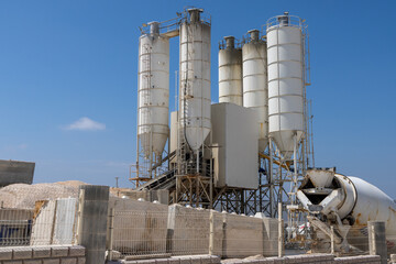 Industrial concrete batching plant with silos and mixer under a clear blue sky © AlgarveVisuals