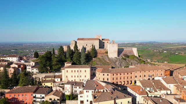 Breathtaking aerial drone view of the medieval Malatesta Fortress in Verucchio overlooking the vast Valmarecchia countryside and Adriatic coast under a clear sky in Emilia-Romagna, Italy