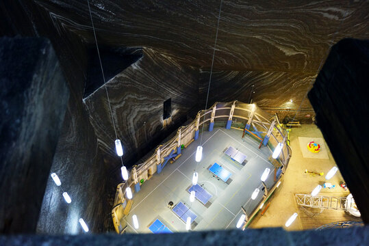 Subterranean recreation center inside Salina Turda with ping-pong tables and playground equipment. Represents adaptive reuse of a salt mine and unique wellness destination inside ancient halite cave.