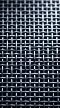 Close-up of a woven metallic wire mesh against a dark background, industrial texture, abstract metal pattern.